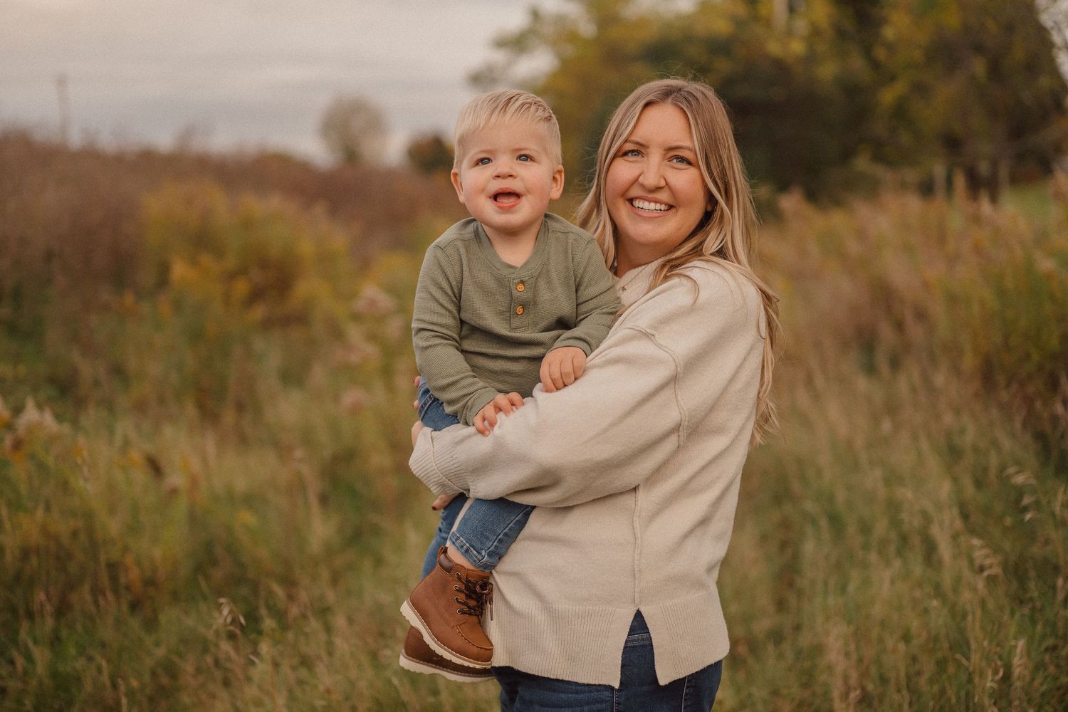 A family shares joyful moments together in a golden autumn field during a lifestyle photography session.