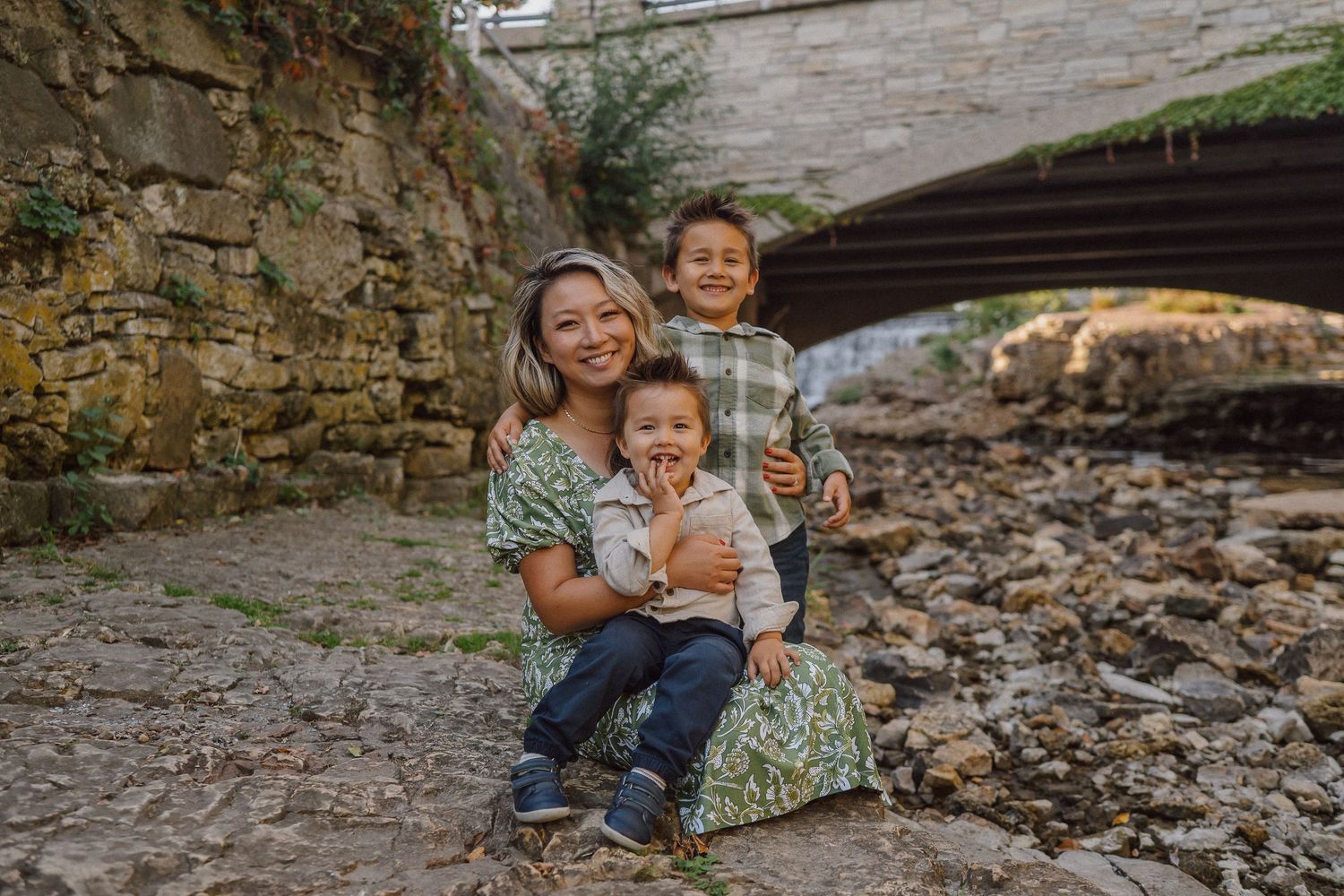 A family enjoys playful moments together on rustic stone steps during an outdoor photo session.