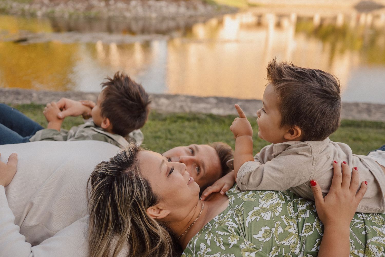 Candid family moment at sunset by a reflective pond with golden light.