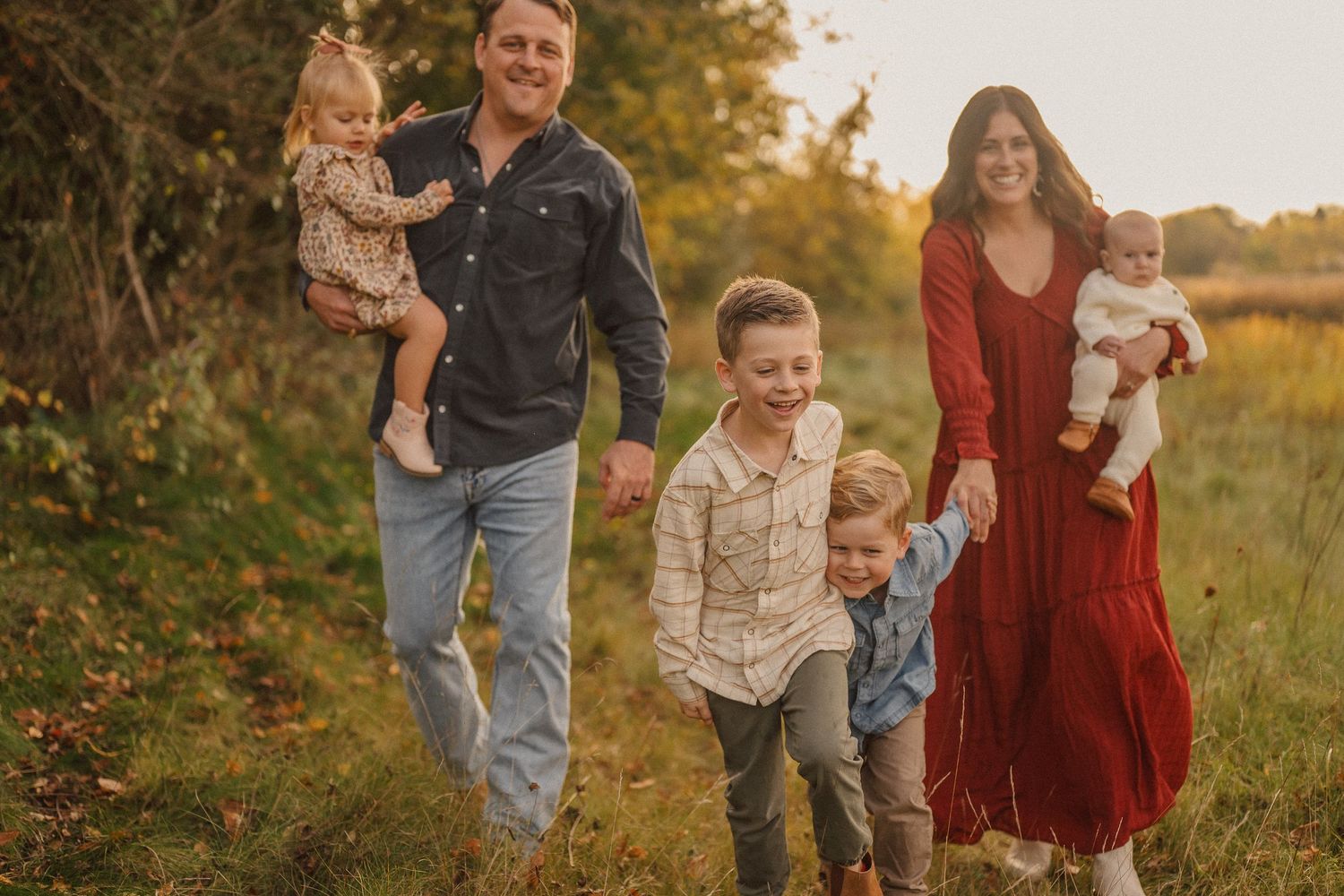 Family group photo session captured in a natural outdoor setting with fall foliage.