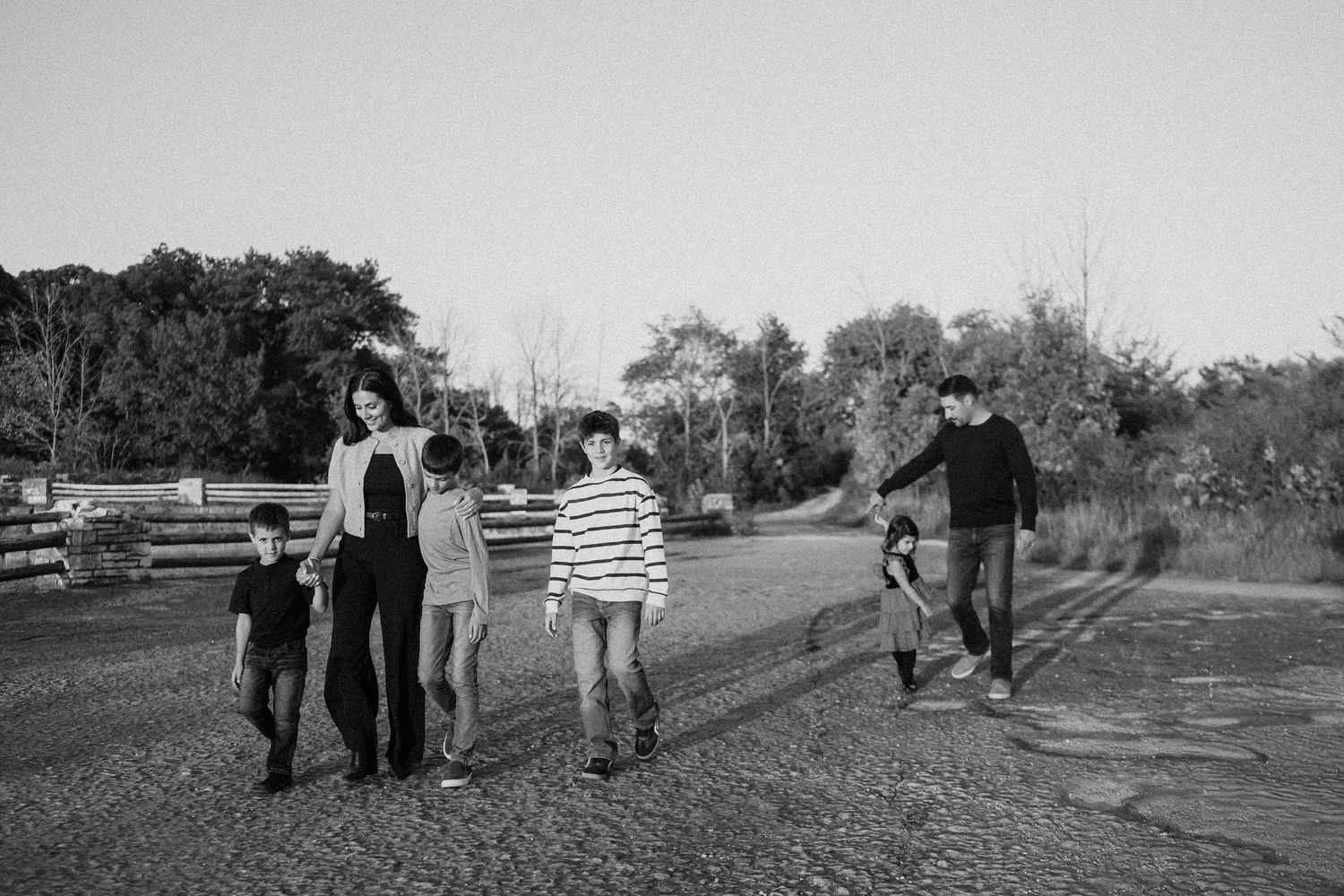 Black and white photo of a family walking together through a grassy field during a photo session.