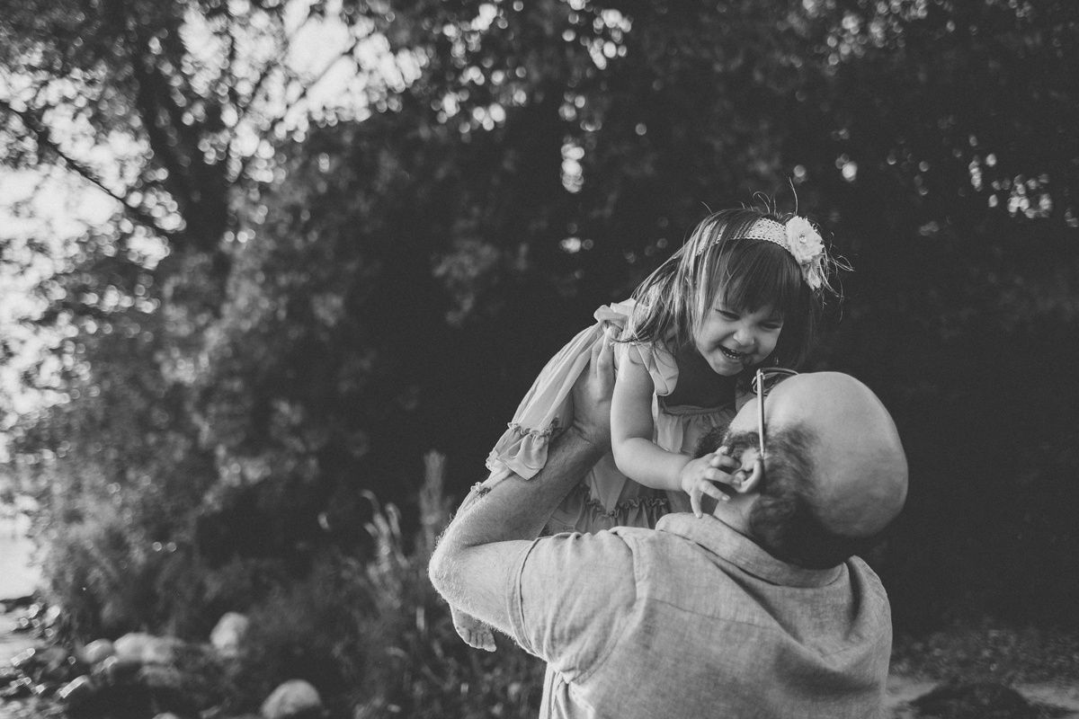 Black and white portrait of joyful playtime between adult and child outdoors.