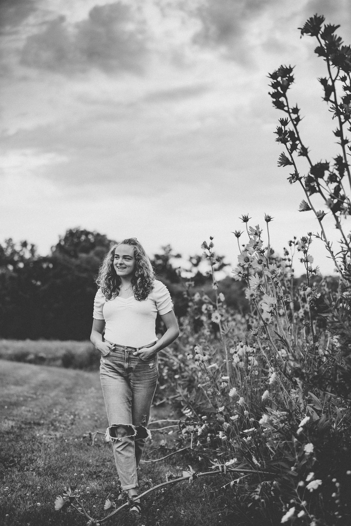 Black and white landscape portrait with flowering plants against cloudy sky.