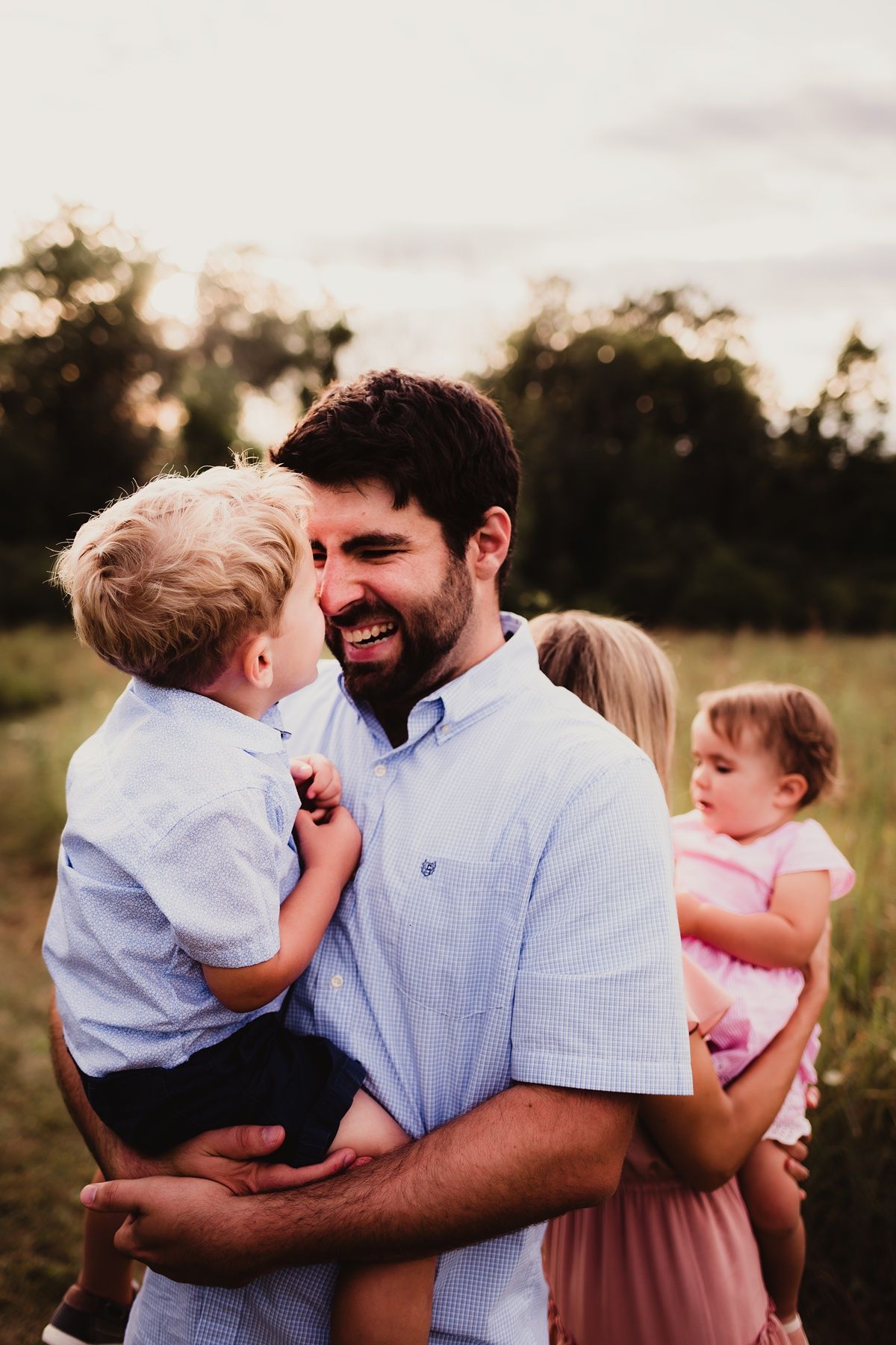 Joyful outdoor family portrait during golden hour in a grassy field.