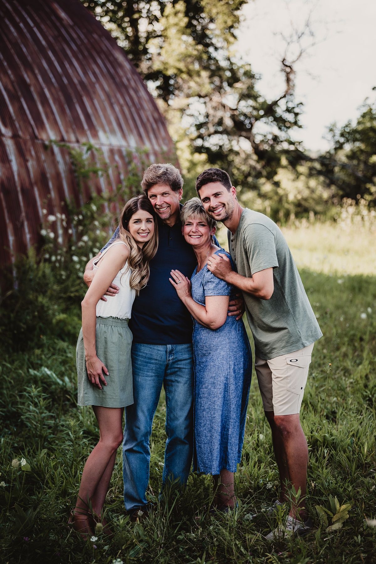 A group portrait taken outdoors near a curved metal barn structure.