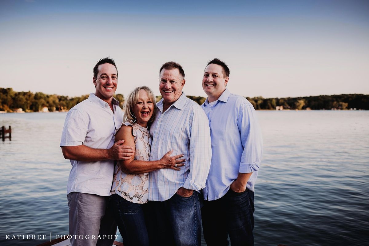 Family of four sharing joyful moment together by the lake at sunset.