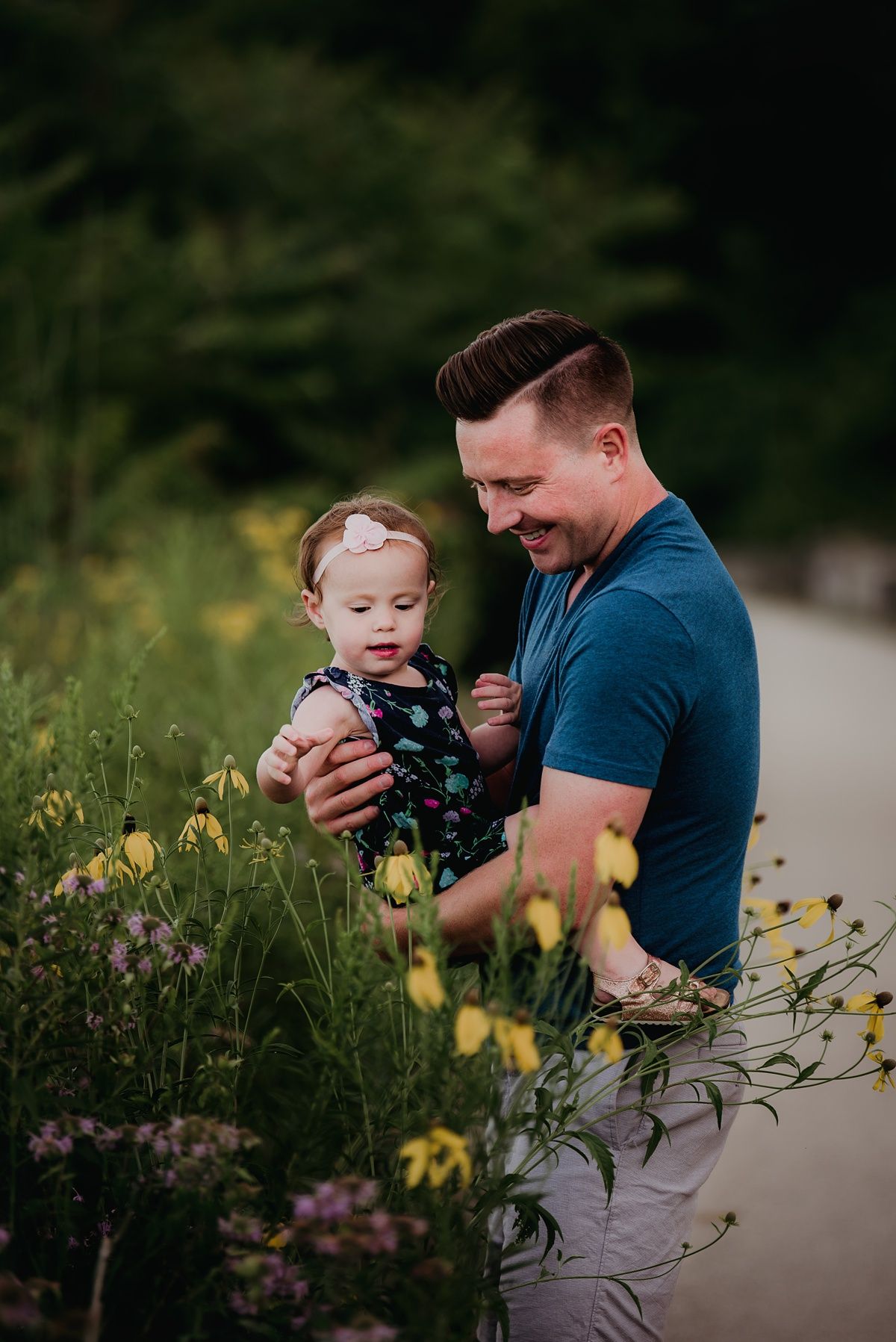 Loving parent-child moment surrounded by yellow wildflowers along a garden path.