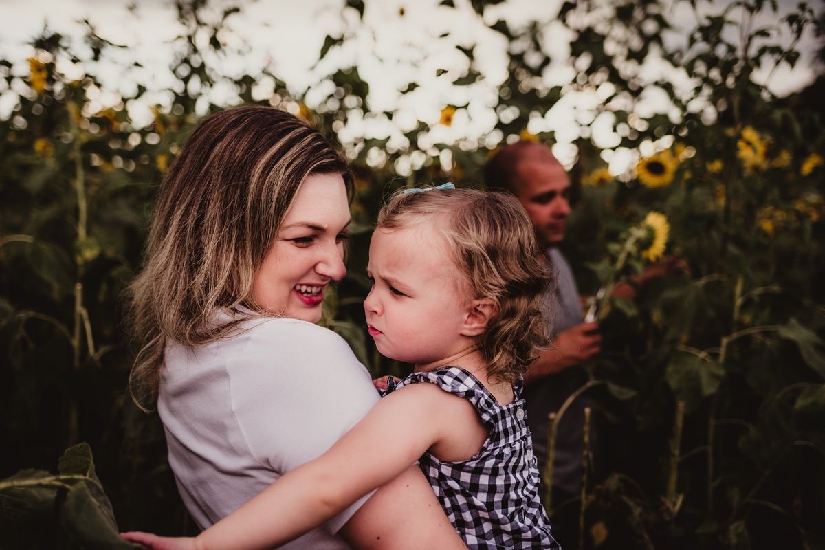 An intimate family moment captured among blooming sunflowers at sunset.