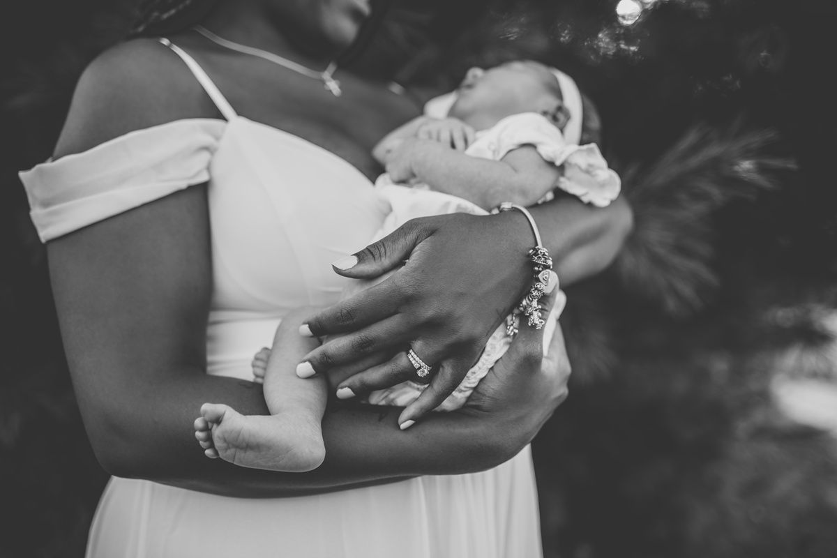 Close-up black and white photo showing gentle hands cradling a newborn baby.