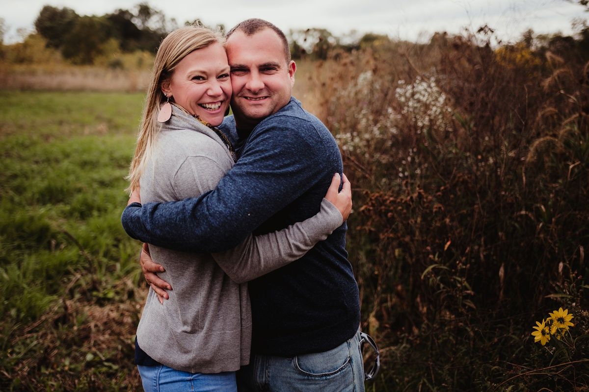 A happy couple shares a warm embrace while laughing together outdoors.