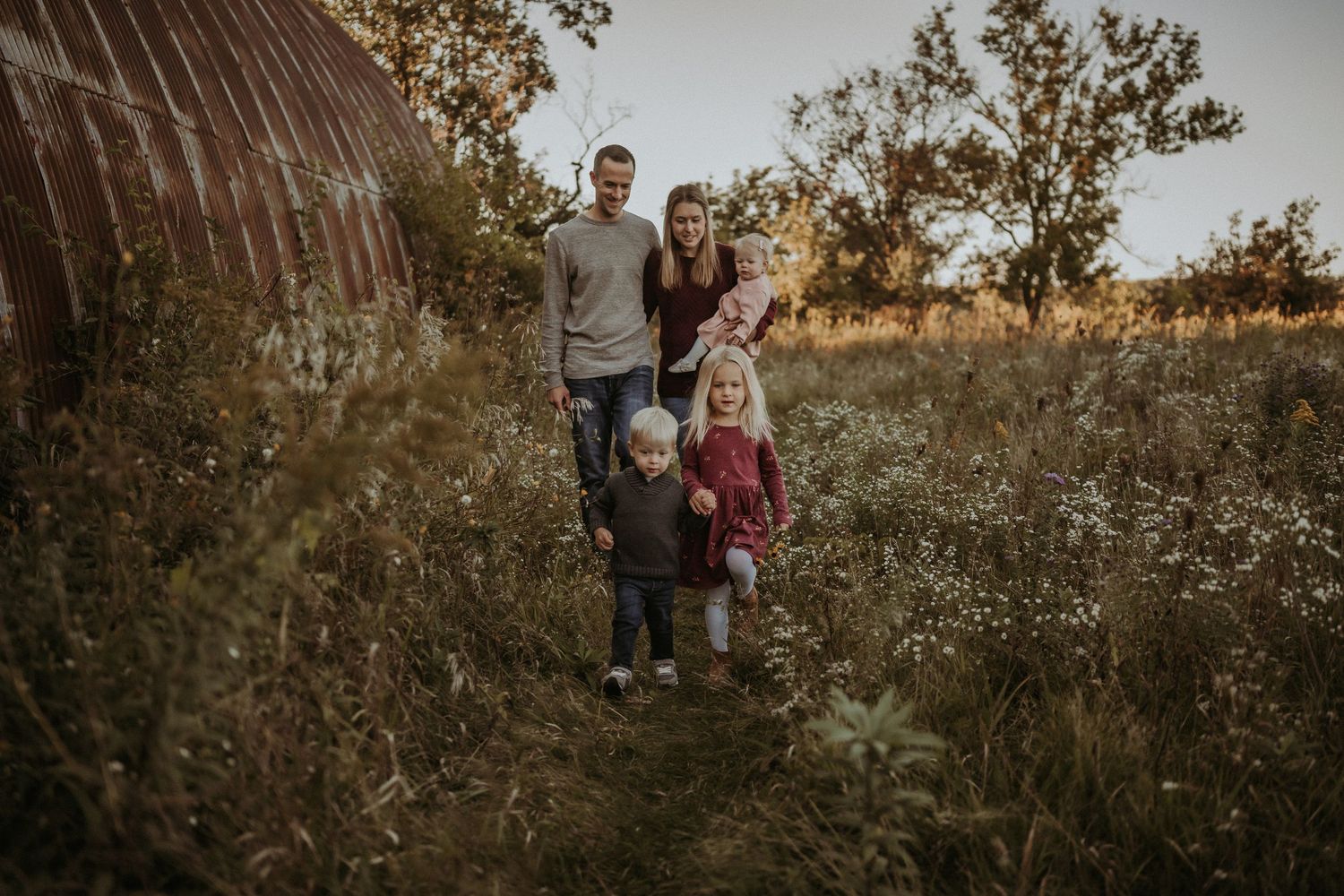 Group portrait in a rustic field against a setting sun and trees.