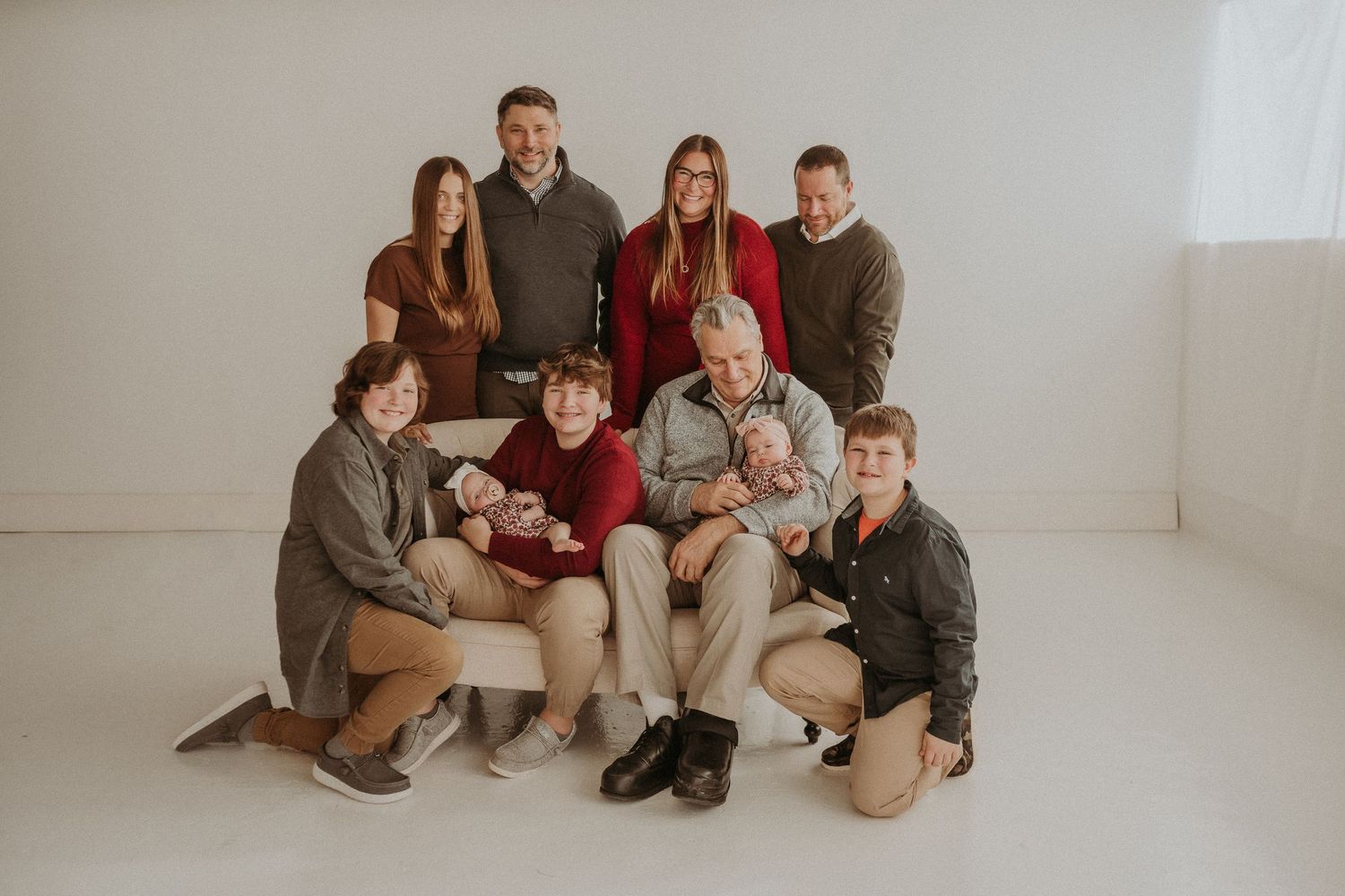 Multi-generational family poses together for a studio portrait in coordinated casual outfits.