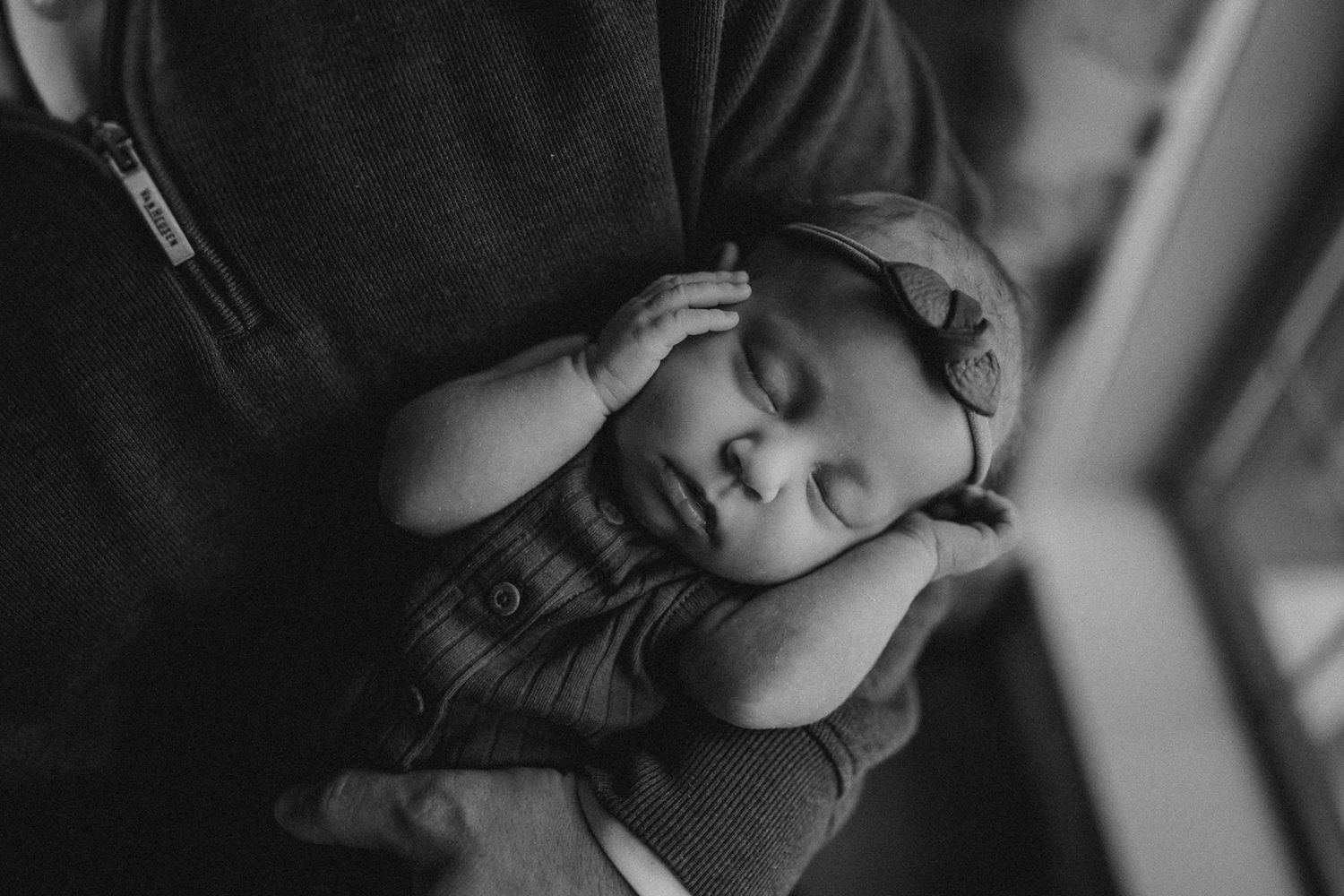 Black and white image of sleeping baby nestled against shoulder.