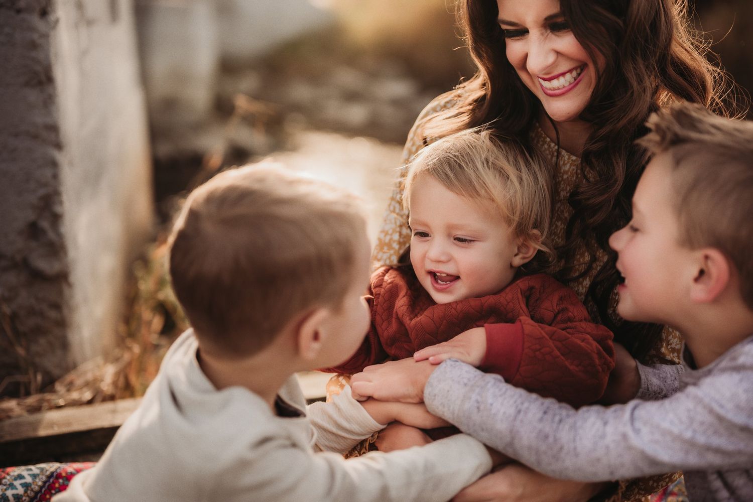 A joyful family moment of shared laughter on a cozy blanket during golden hour.