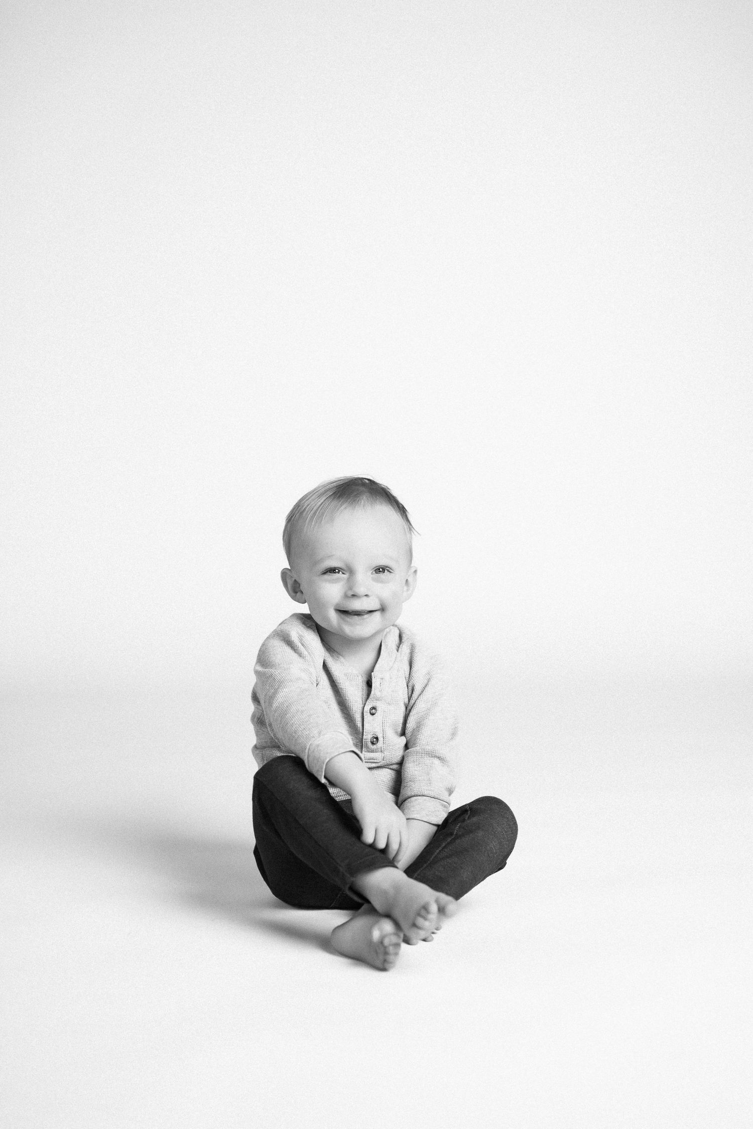 Series of black and white studio portraits showing a young child sitting in various relaxed poses.