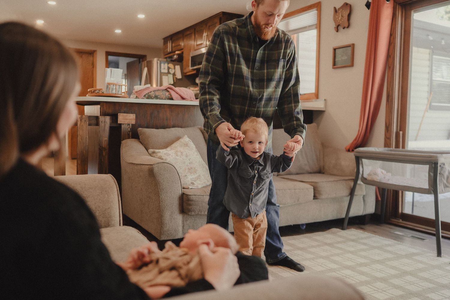 An intimate family moment captured in a sunlit living room with warm natural lighting.