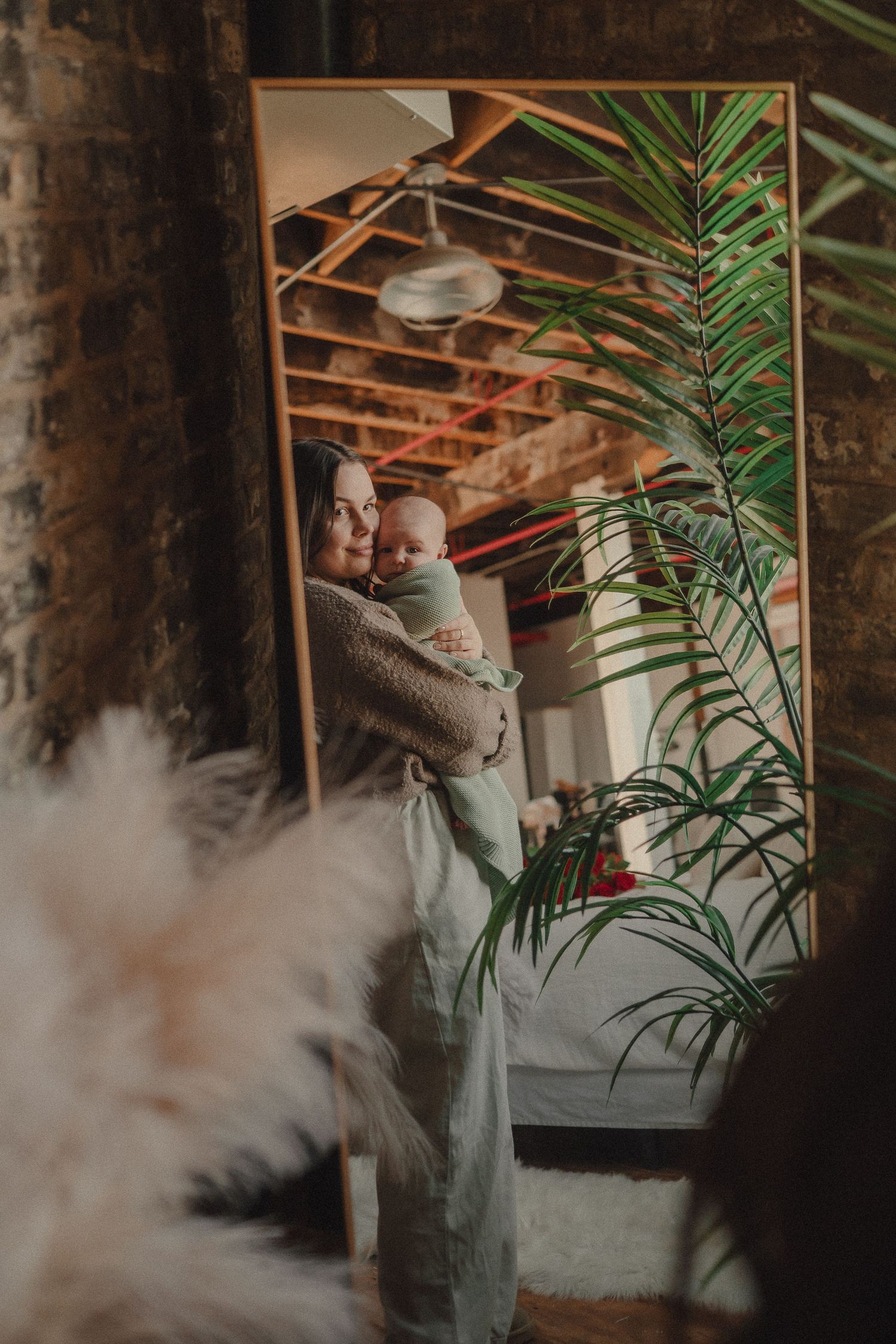 Artistic family photography in industrial space with tropical plants and soft lighting.