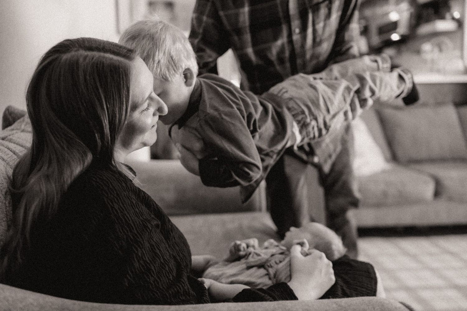 A series of tender interactions unfold on a couch in a warmly lit living space.