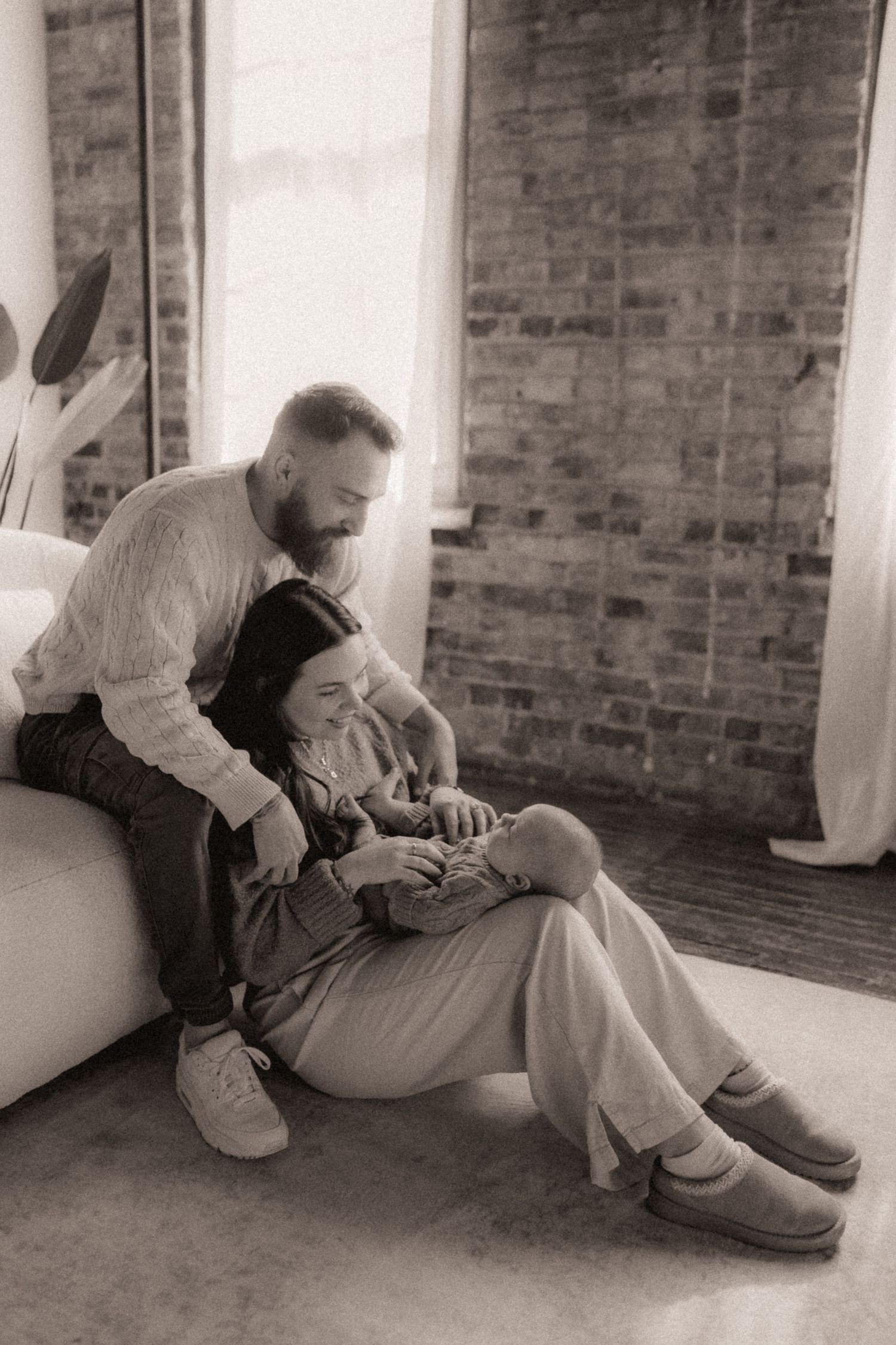 Black and white photo series showing tender moments between two people sitting against a brick wall.
