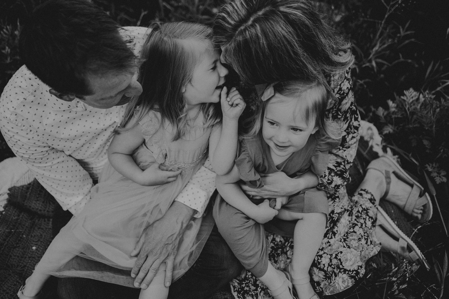 An intimate black and white family portrait captured during a playful outdoor moment.