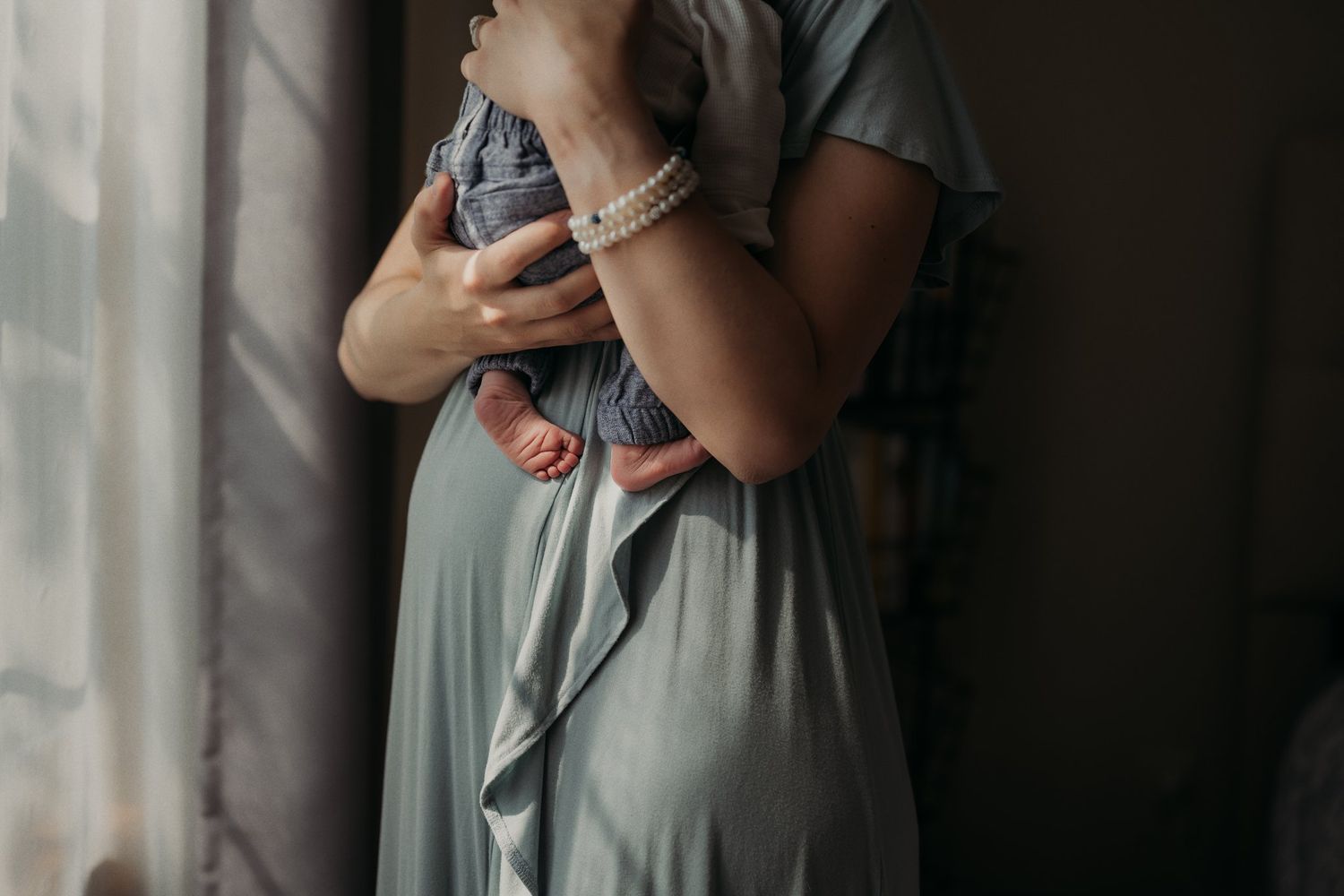 Close-up portrait showing gentle embrace in dramatic window lighting.