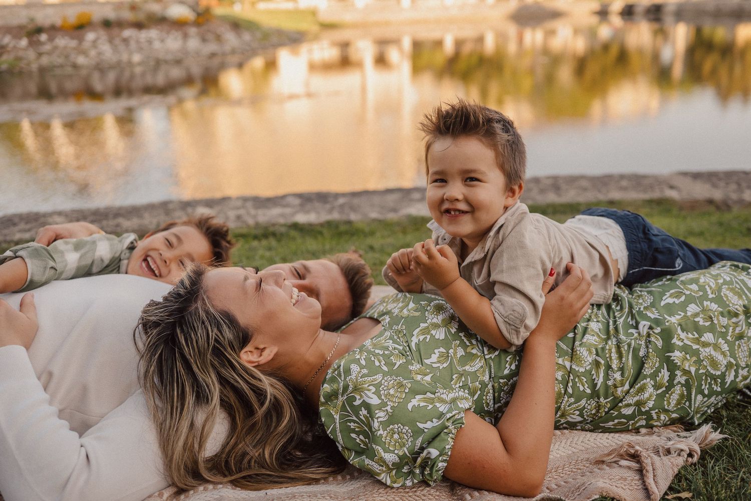 Family lying together on grass during sunset creating playful outdoor portraits.