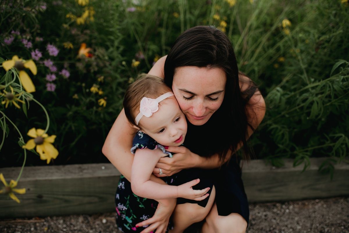 Intimate family portrait in a lush garden with blooming yellow and purple flowers.