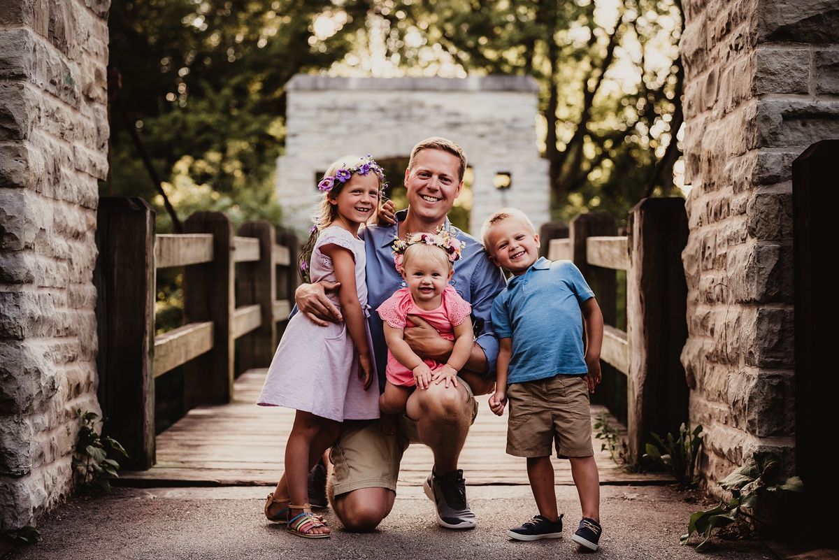 A cheerful family photo on a wooden bridge with stone pillars.