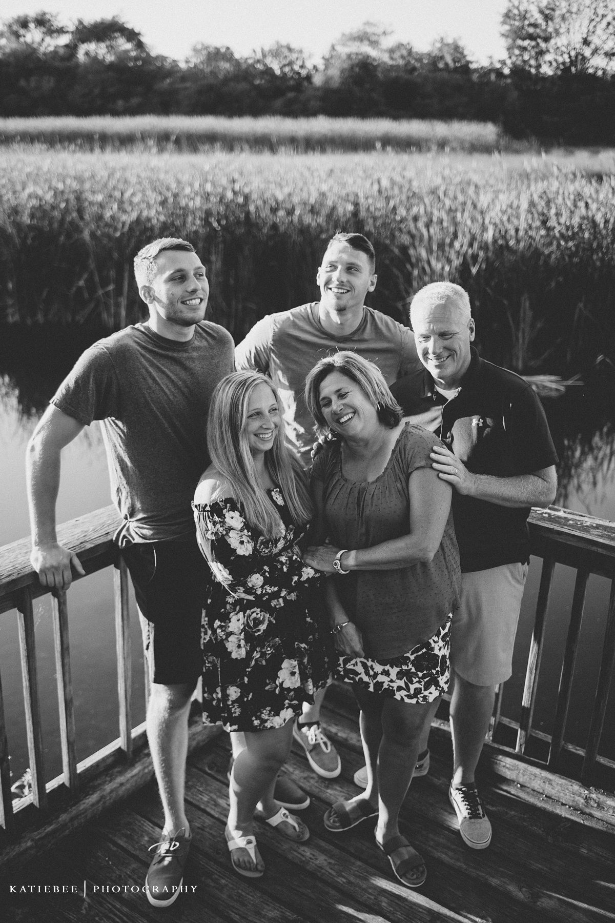 Black and white photo of group laughing together on outdoor deck.