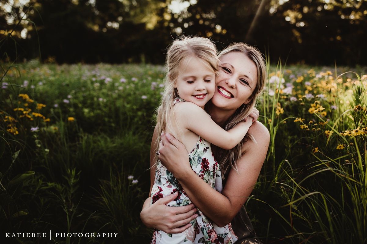 Warm sunset portrait capturing a loving embrace among wildflowers in a summer field.