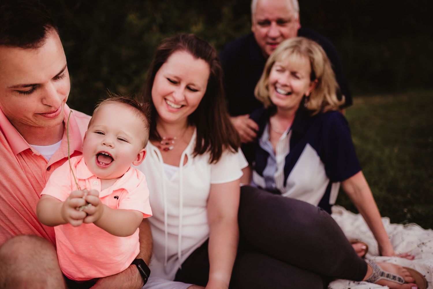Happy family gathered on a blanket outdoors sharing laughs together.
