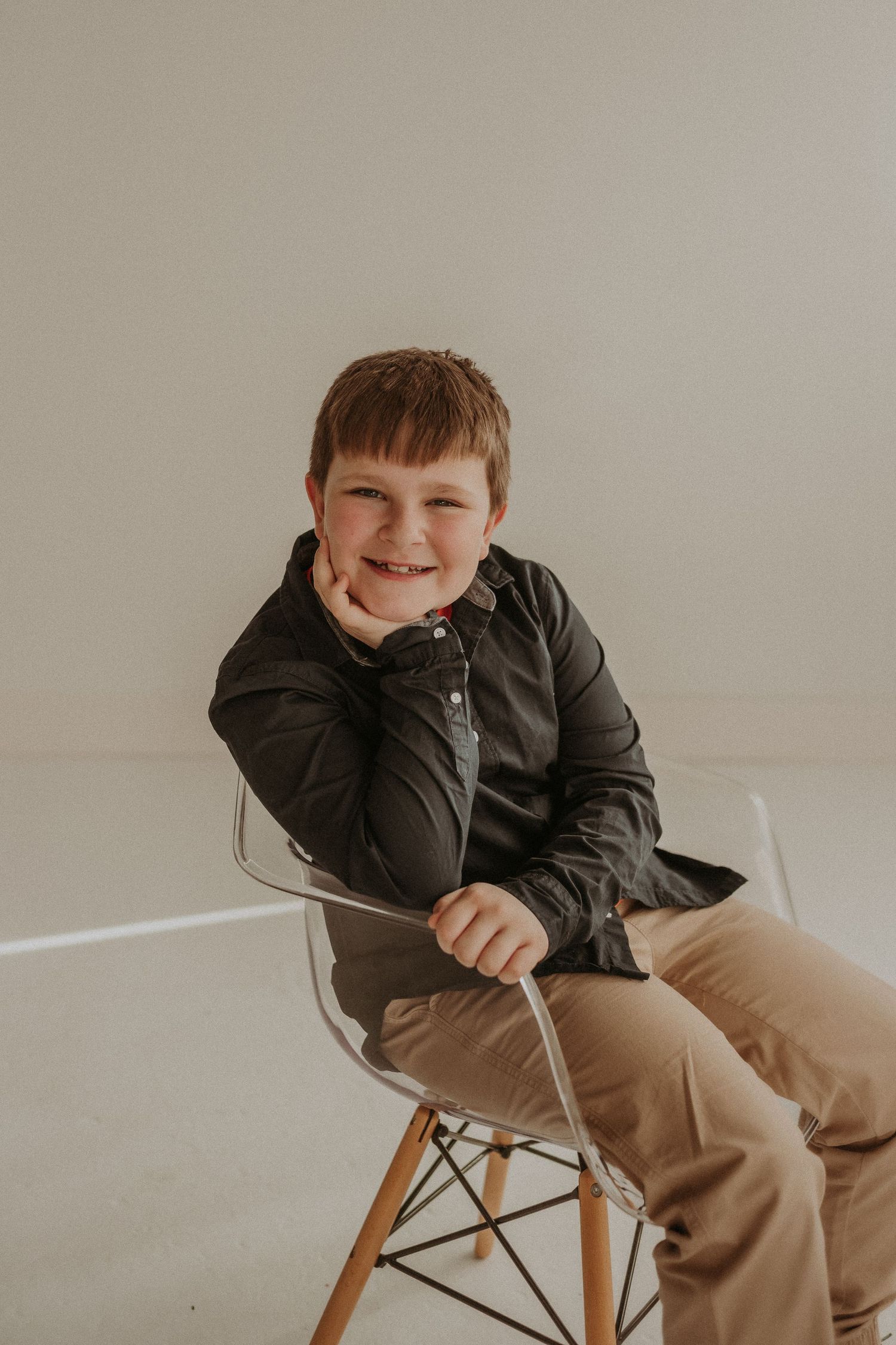 A relaxed portrait of someone sitting in an Eames-style chair wearing casual attire.