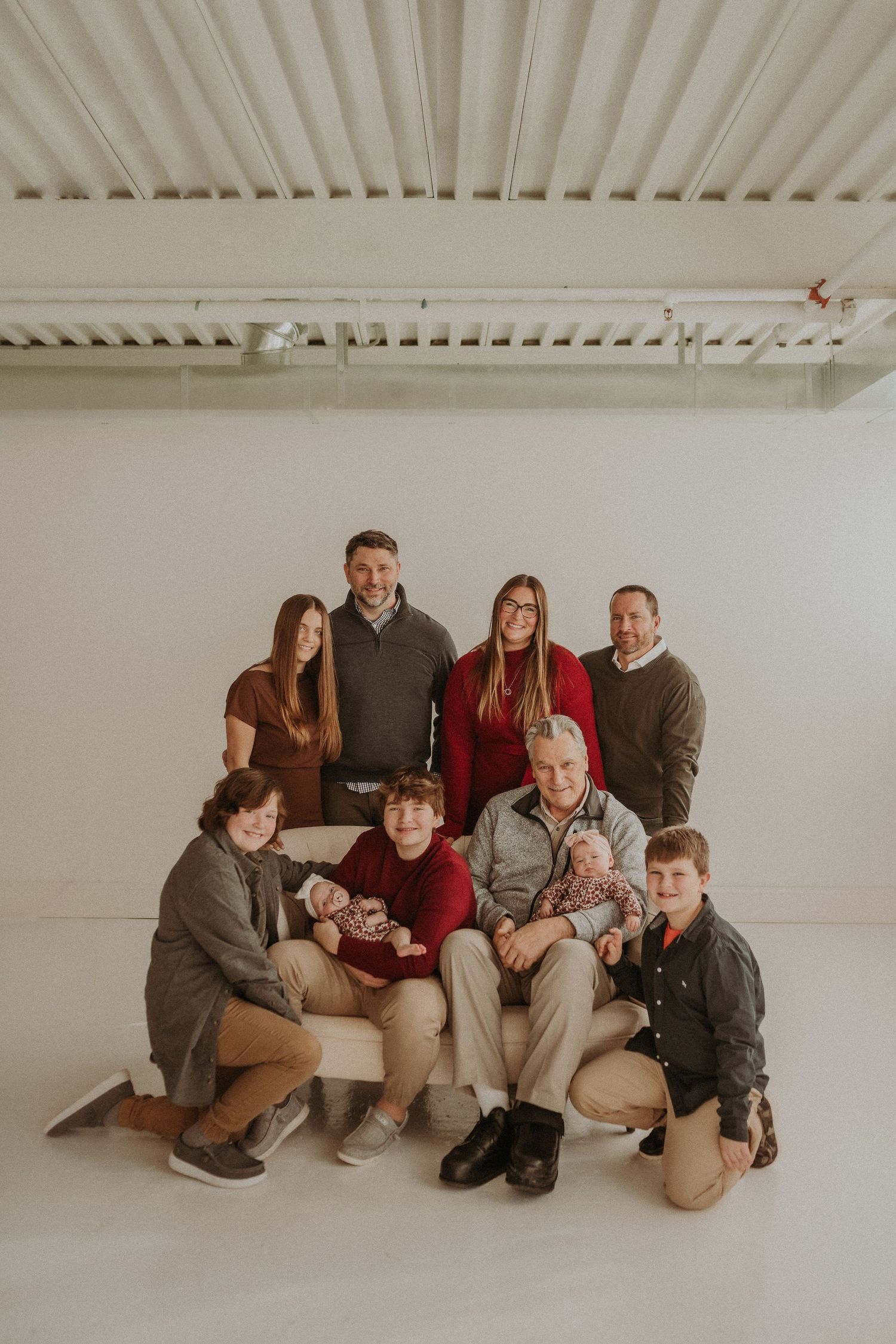 Extended family members pose together for a professional portrait against a white backdrop.