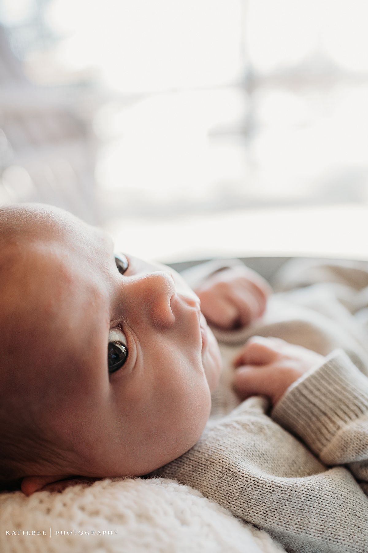 Side profile of infant in knit sweater resting on textured surface.