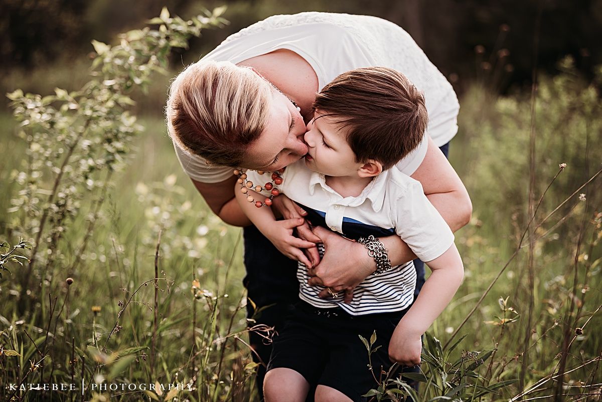 Candid moment of affection and laughter in a sunny meadow with wildflowers.
