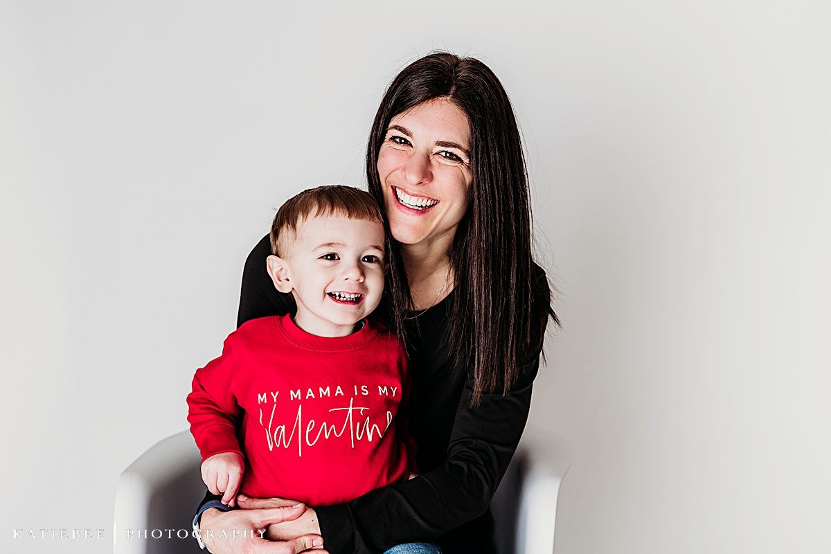 Sweet candid portrait of family members sharing laughter against white backdrop.