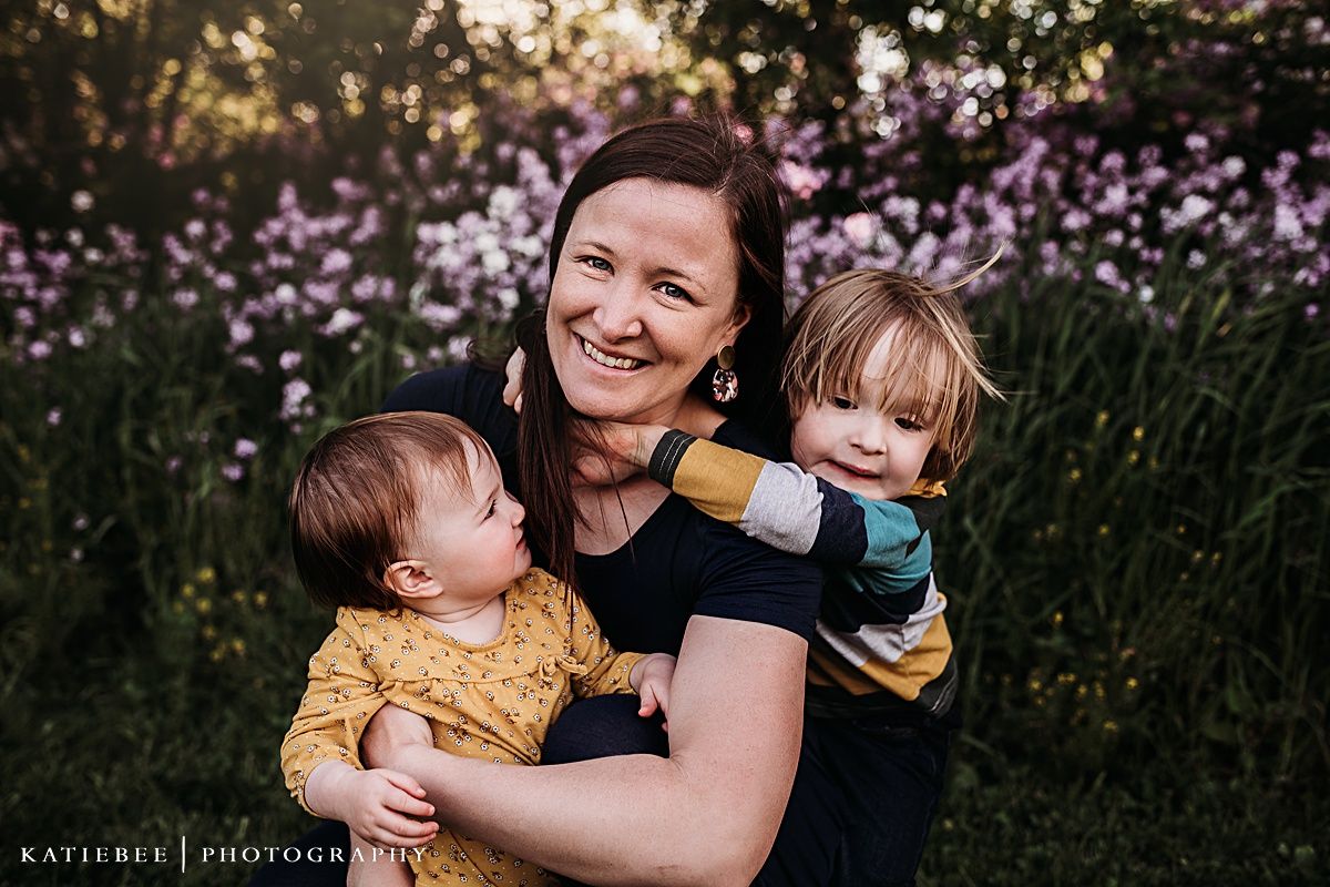 Outdoor family portrait with purple flowers in the background during golden hour.