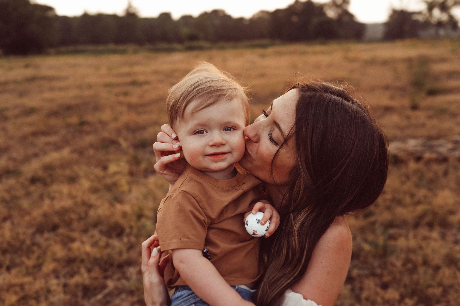 A sweet moment between parent and child in a rustic field during golden hour.