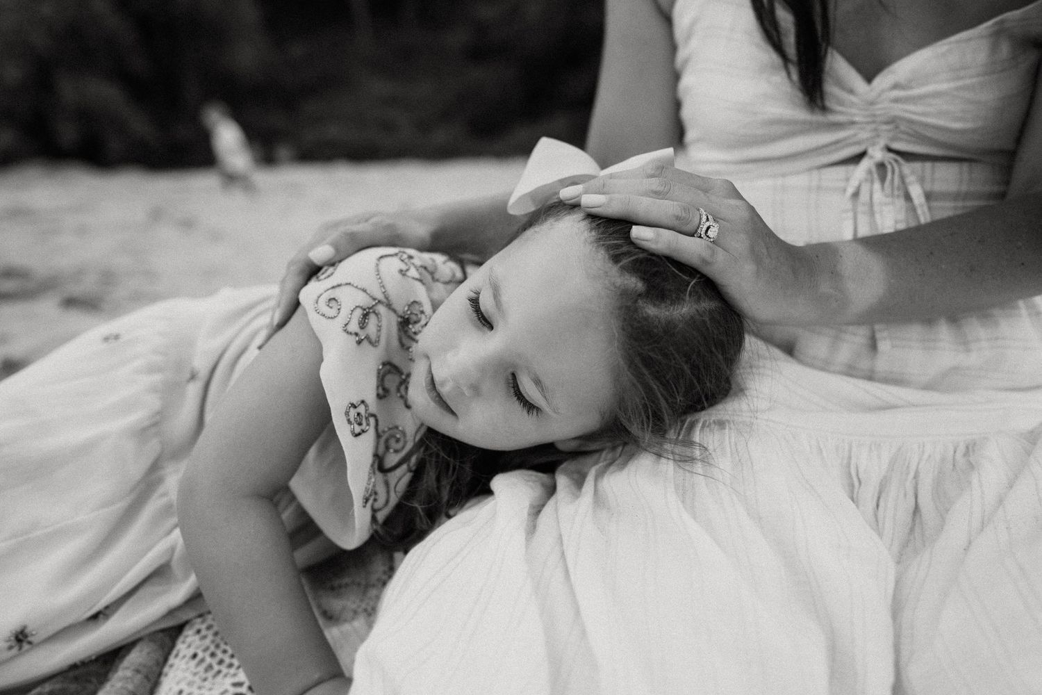 A gentle black and white portrait showing a tender moment between two people outdoors.