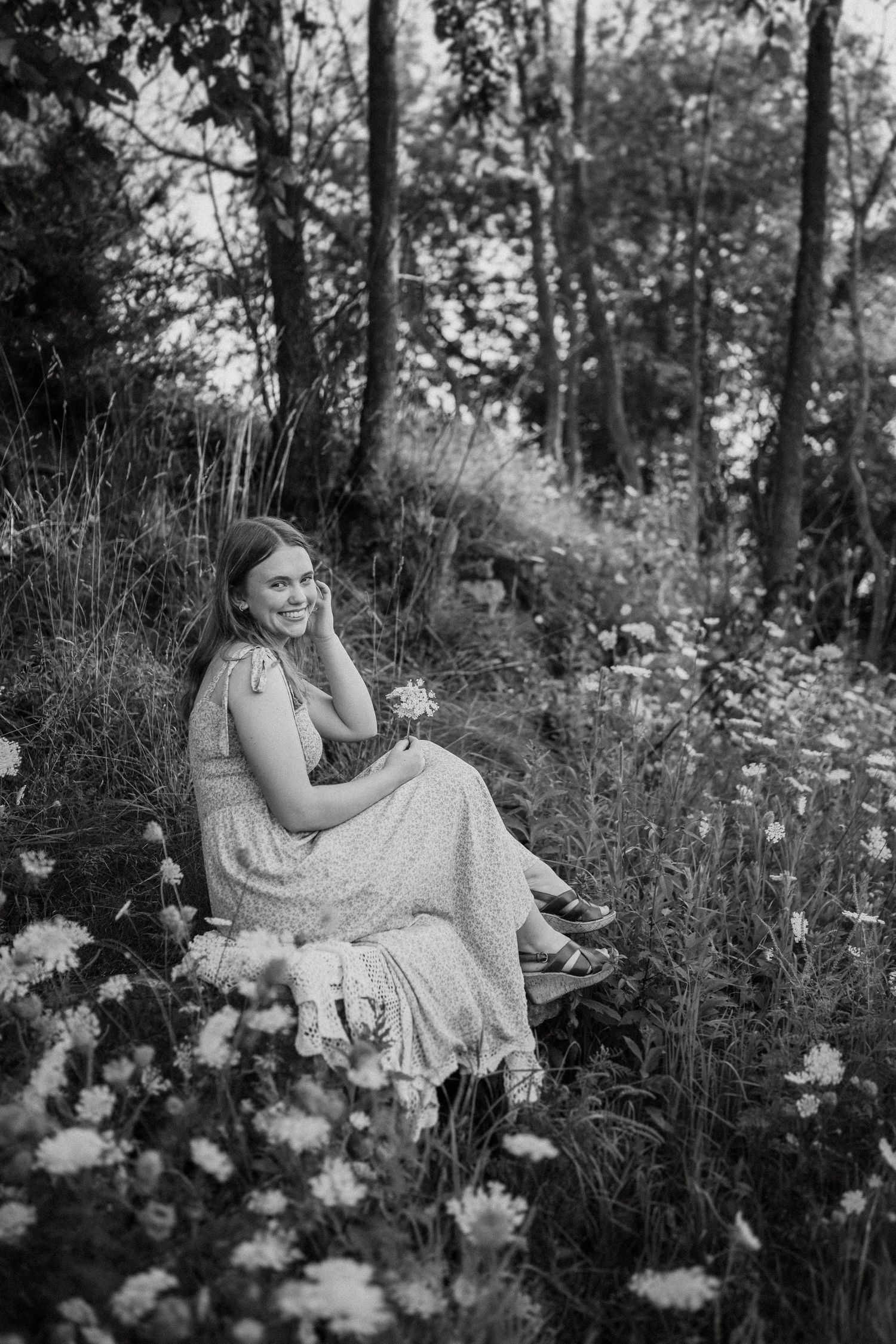 A black and white portrait in a meadow filled with delicate flowers and natural light.