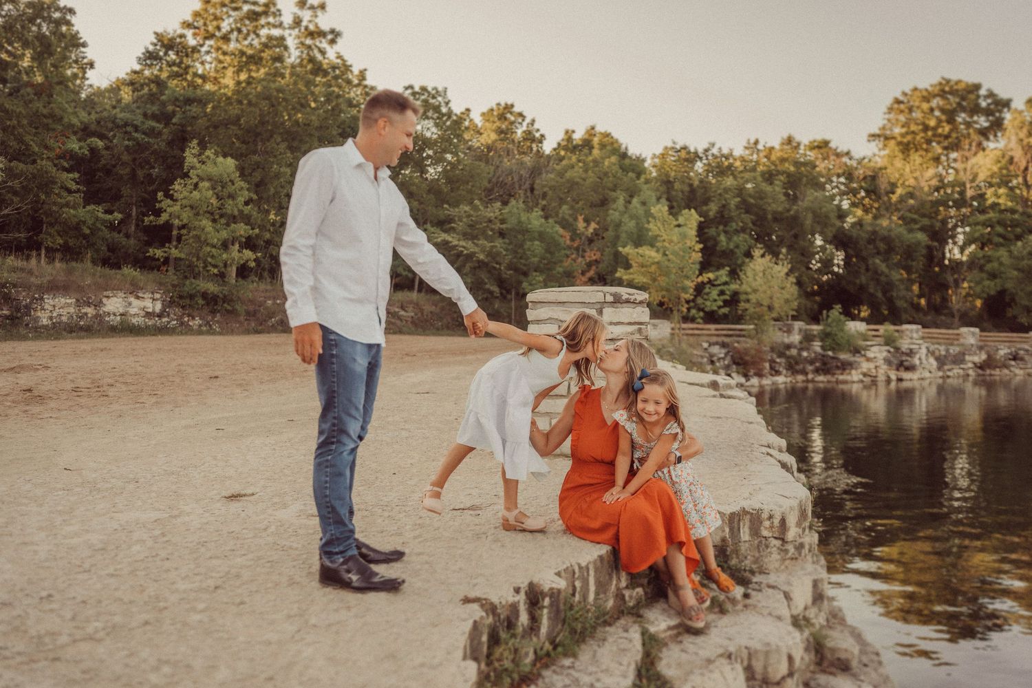 Sunset family moment captured by a lake with stone pillars and natural scenery.