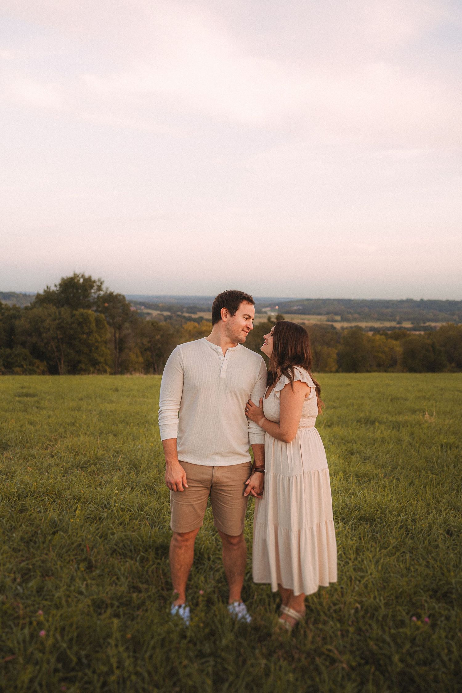 Couple sharing an intimate moment in a hilltop meadow during golden hour.