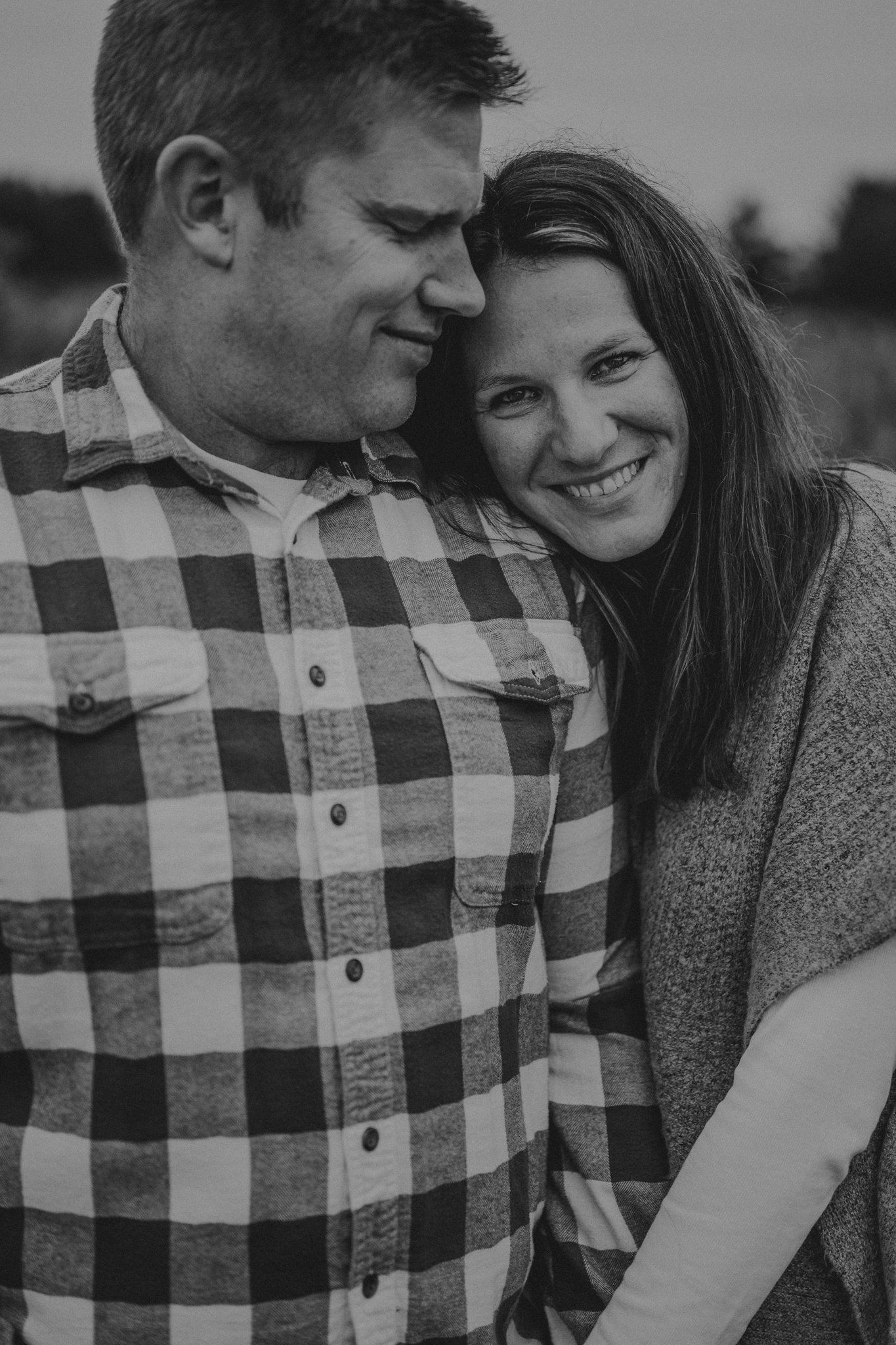 A black and white close-up of a couple sharing an intimate moment outdoors.
