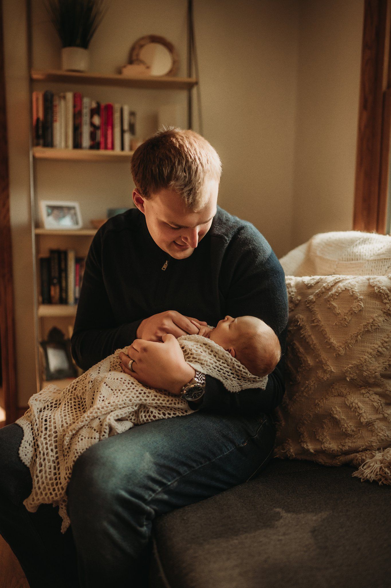 A tender moment captured as someone cradles a baby wrapped in a knit blanket.