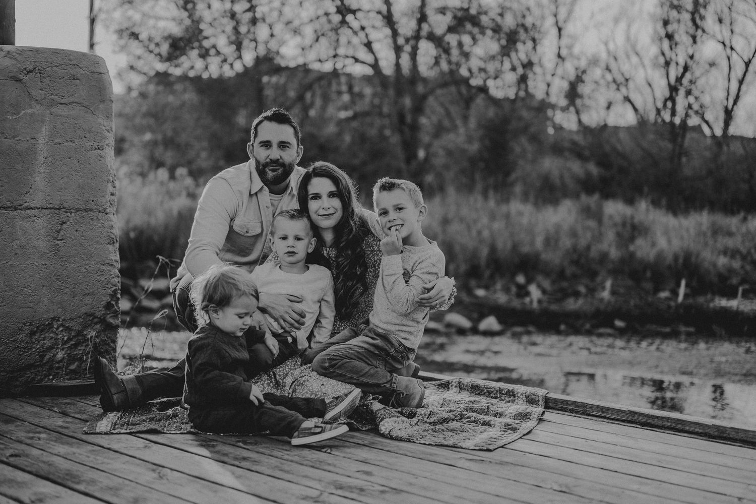 Black and white portrait of family sitting together on outdoor deck.