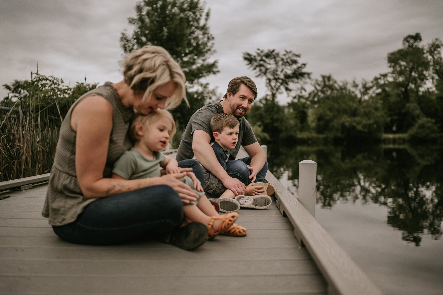 Family spending time together on wooden dock by peaceful pond.