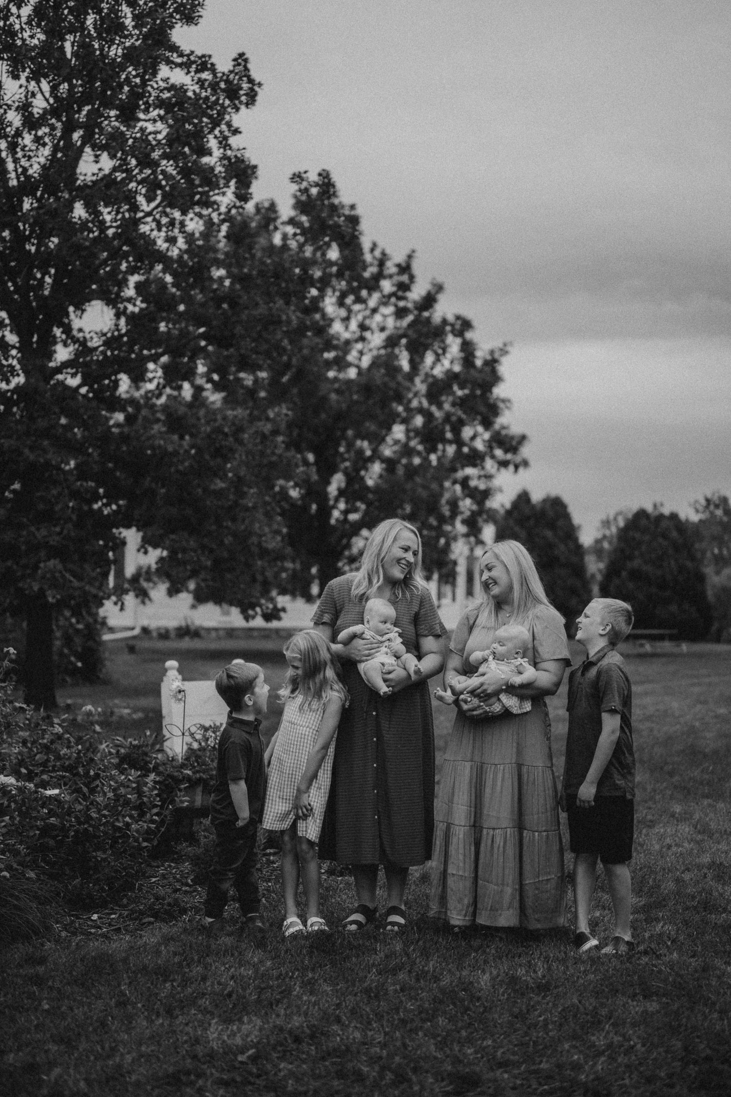 Group standing together outdoors in black and white photo with trees and garden in background.
