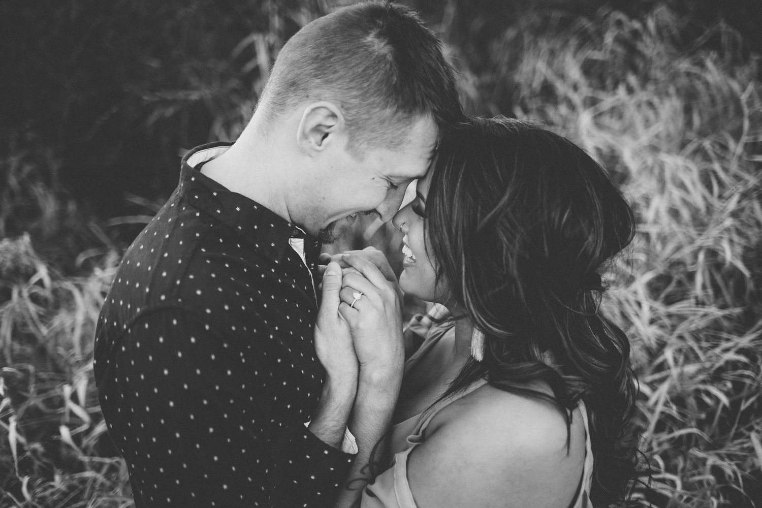 Black and white intimate portrait of couple sharing a tender moment outdoors.
