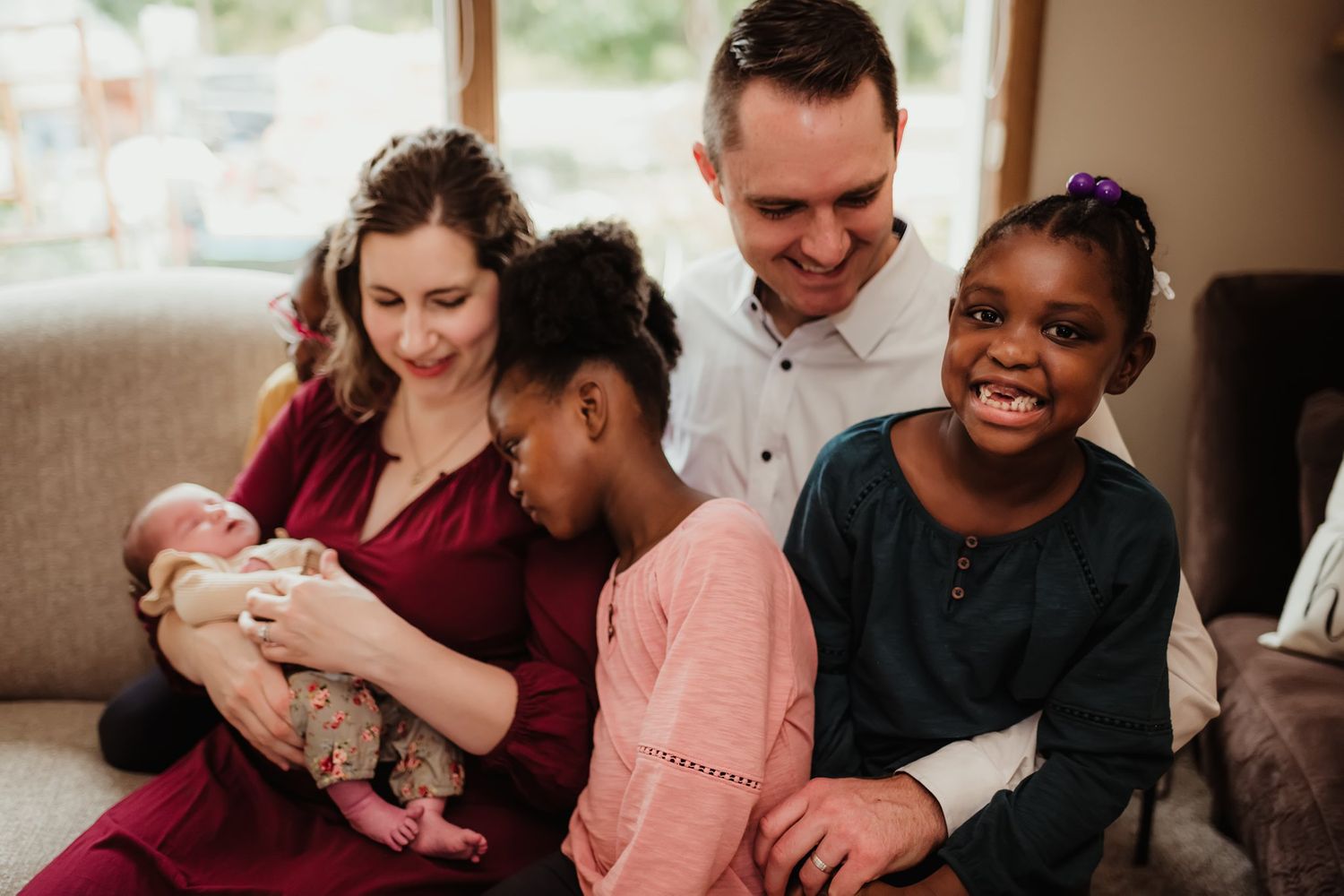 Family sharing joyful moment together on couch while looking at newborn baby.