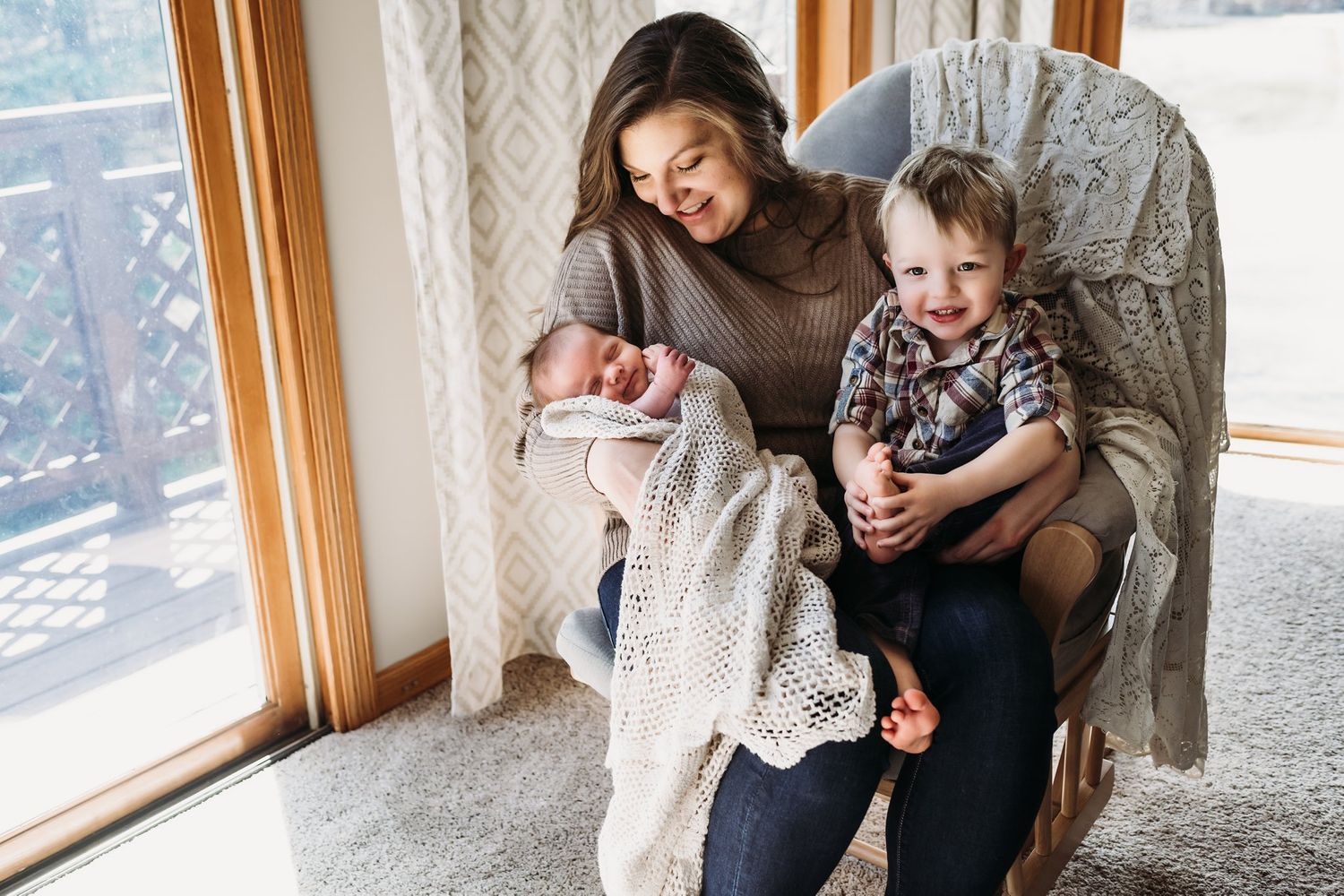 Tender family moment shared in comfortable chair by bright window.